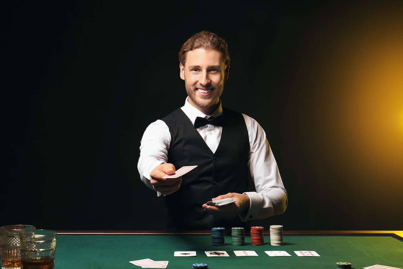 дилер лайв-казино с картами и фишками в руке и на столе